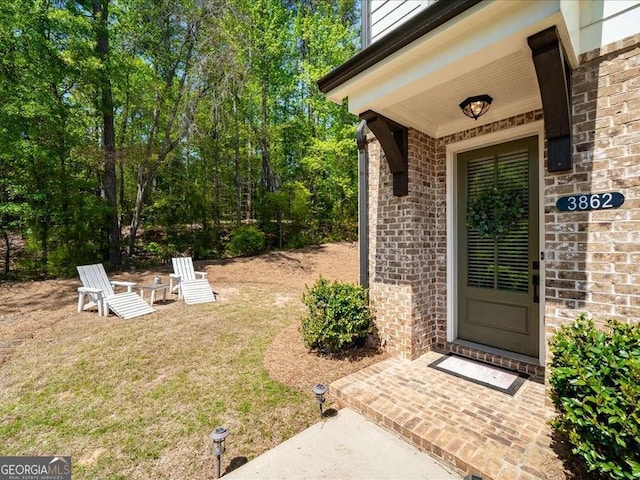 property entrance with brick siding and a lawn