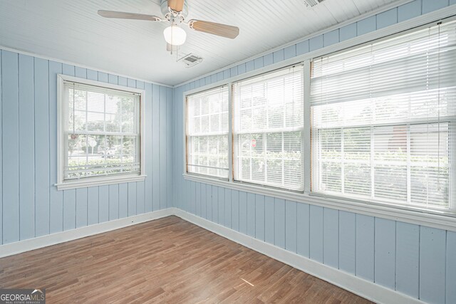 unfurnished room with ceiling fan, baseboards, wood finished floors, and plenty of natural light