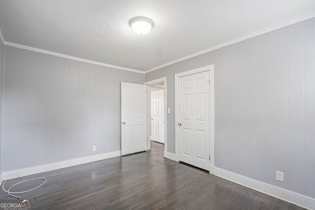 empty room with crown molding, baseboards, and dark wood-style flooring