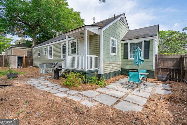 back of house with a storage unit, a patio area, an outbuilding, and fence