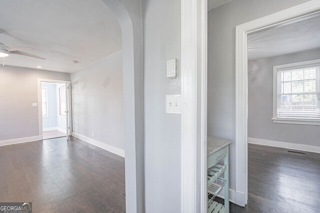 corridor with baseboards, dark wood-style floors, arched walkways, and recessed lighting