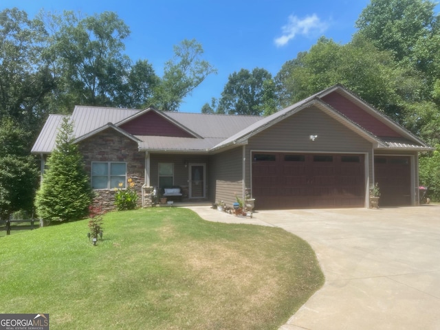 view of front of property featuring a front lawn, driveway, stone siding, metal roof, and a garage