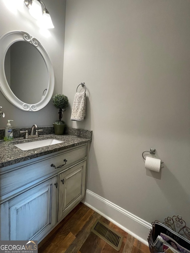 bathroom featuring baseboards, wood finished floors, visible vents, and vanity