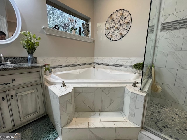 full bath with a garden tub, vanity, and tiled shower