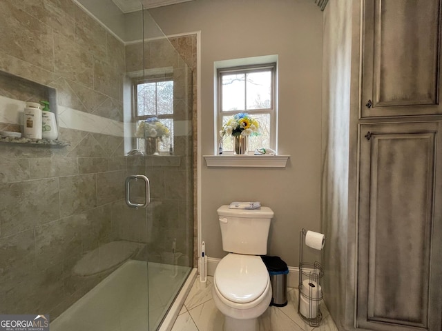 bathroom with baseboards, toilet, ornamental molding, and a stall shower