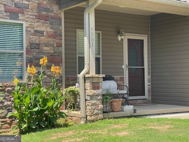 doorway to property with stone siding and a porch