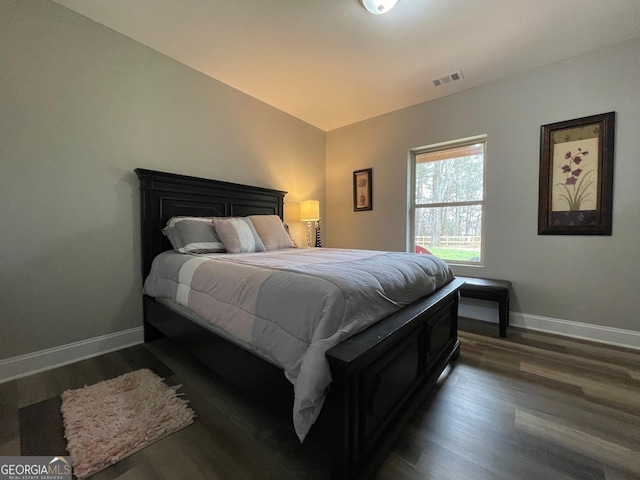 bedroom featuring dark wood-style floors, baseboards, vaulted ceiling, and visible vents