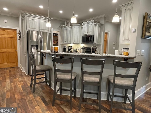 kitchen with a peninsula, dark wood finished floors, crown molding, and stainless steel appliances