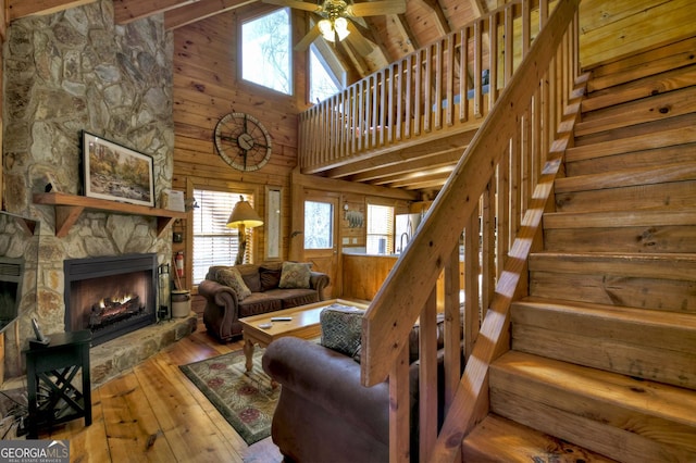638 Cohutta Mountain Rd, Blue Ridge, GA 30513 - living room featuring wooden walls, a ceiling fan, wood-type flooring, a fireplace, and high vaulted ceiling