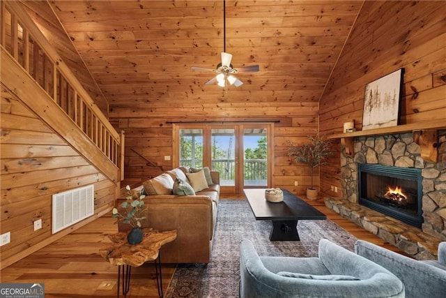 living area with lofted ceiling, wood finished floors, visible vents, and a fireplace