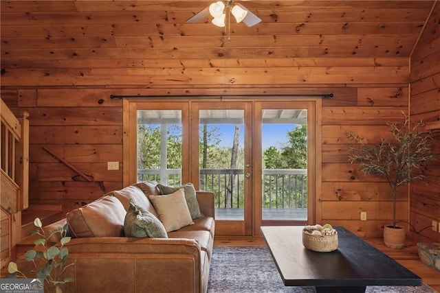 living room featuring lofted ceiling, wood finished floors, wood walls, and a ceiling fan