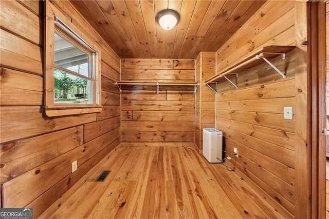 laundry area with wooden walls, wood ceiling, light wood finished floors, visible vents, and laundry area
