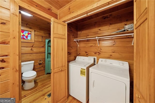 laundry area featuring washing machine and clothes dryer, light wood finished floors, wood walls, wooden ceiling, and laundry area