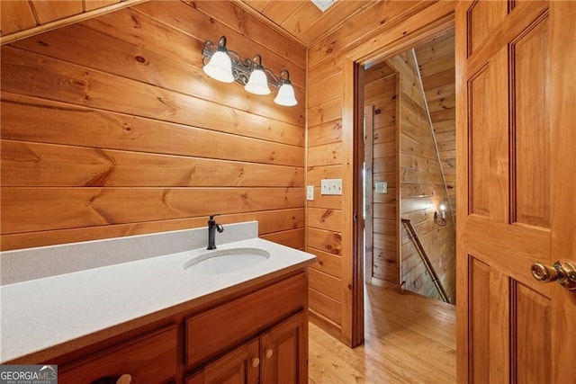 bathroom with wood finished floors, wood walls, and vanity