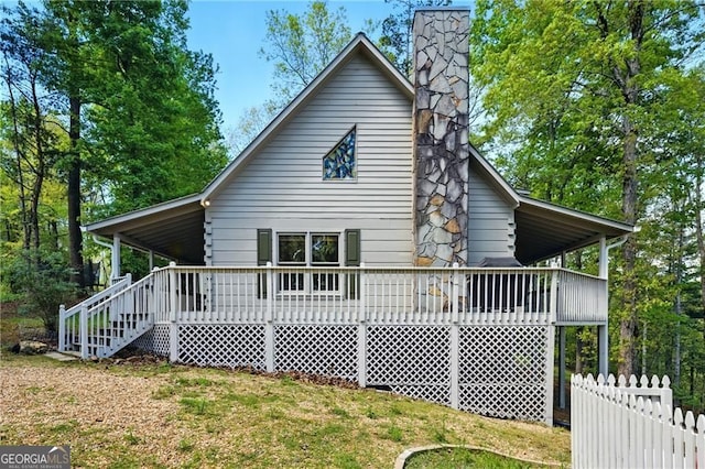 rear view of property featuring fence, a lawn, and a chimney