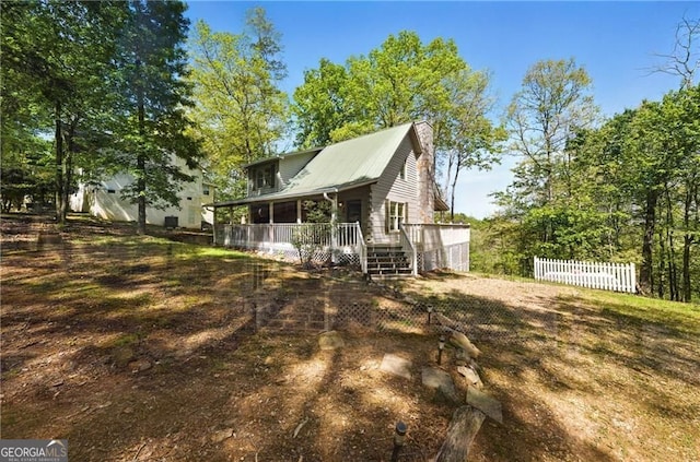 rear view of house featuring fence, a chimney, and metal roof