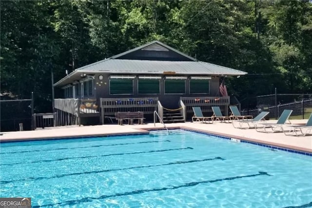 community pool featuring a patio, fence, and a deck