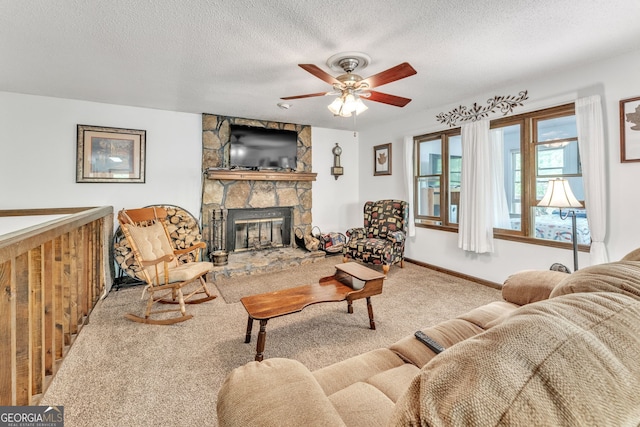 carpeted living area featuring baseboards, ceiling fan, a fireplace, and a textured ceiling
