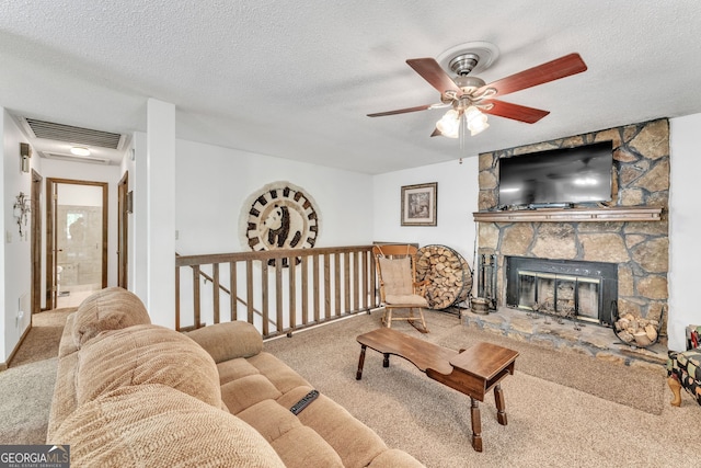living area featuring ceiling fan, a fireplace, a textured ceiling, carpet, and visible vents