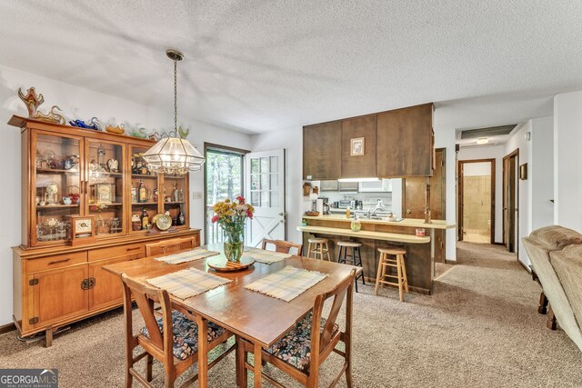 dining space featuring a textured ceiling, light colored carpet, and an inviting chandelier