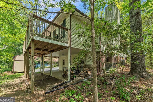 rear view of house featuring a wooden deck, a chimney, and a patio area
