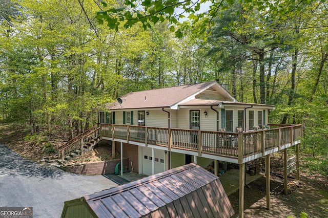 rear view of property with stairway, a deck, and a garage