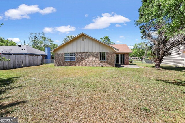 767 Madison Dr, Hinesville, GA 31313 - rear view of house with a fenced backyard, brick siding, a yard, and a patio