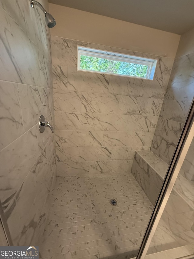 full bathroom with a tile shower and a healthy amount of sunlight