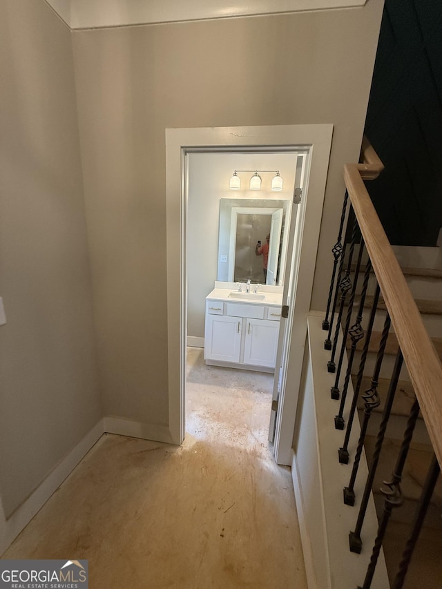 hall featuring baseboards, a sink, and stairs