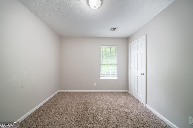 carpeted spare room featuring baseboards, a textured ceiling, and visible vents