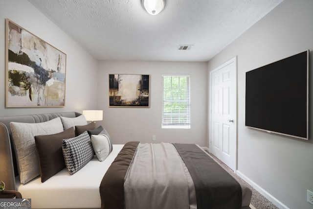 bedroom with visible vents, carpet flooring, a textured ceiling, and baseboards