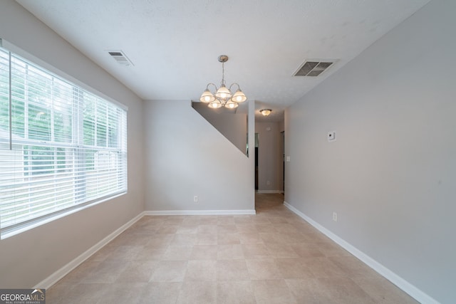 unfurnished dining area with baseboards, a notable chandelier, and visible vents