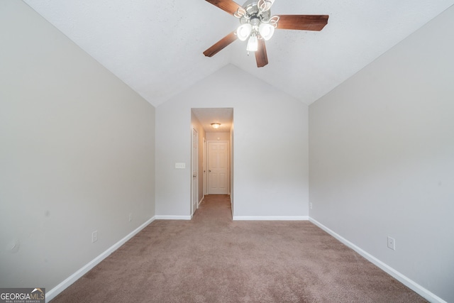 interior space featuring ceiling fan, vaulted ceiling, light carpet, and baseboards