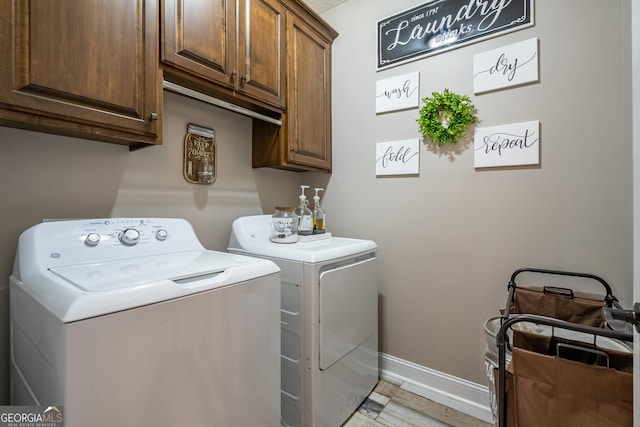 clothes washing area with washing machine and clothes dryer, baseboards, and cabinet space