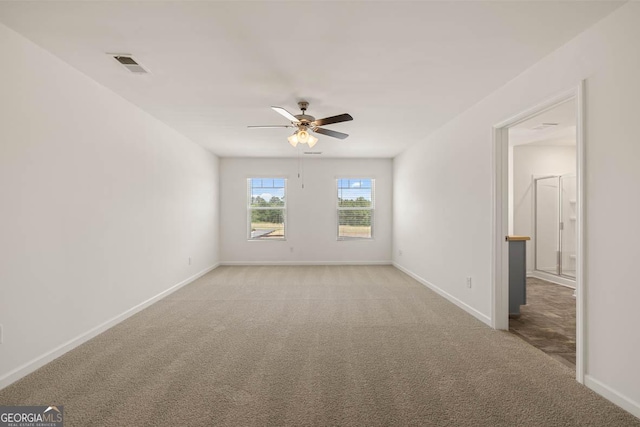 empty room with light carpet, a ceiling fan, visible vents, and baseboards