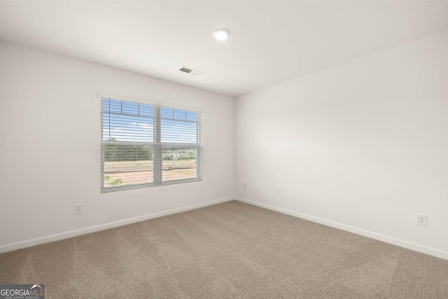 spare room featuring carpet floors, visible vents, and baseboards