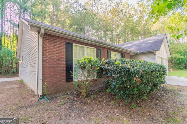 view of side of home featuring an attached garage and brick siding