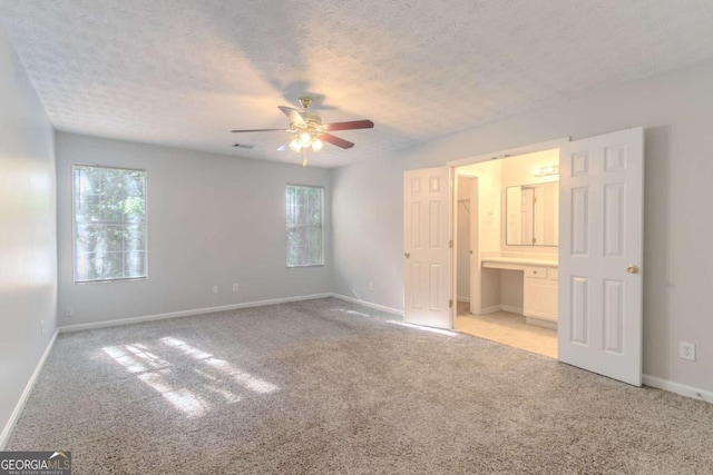 unfurnished bedroom featuring light colored carpet, ensuite bathroom, and baseboards