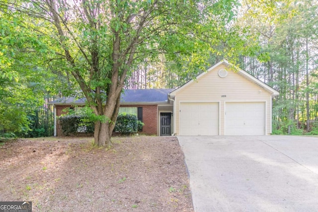 single story home featuring concrete driveway, brick siding, and an attached garage