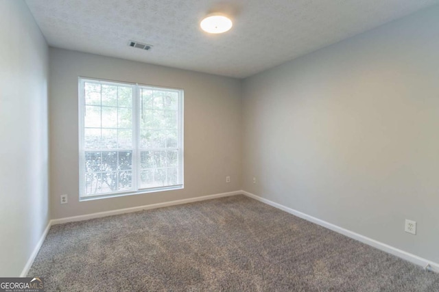 carpeted empty room featuring plenty of natural light, visible vents, baseboards, and a textured ceiling