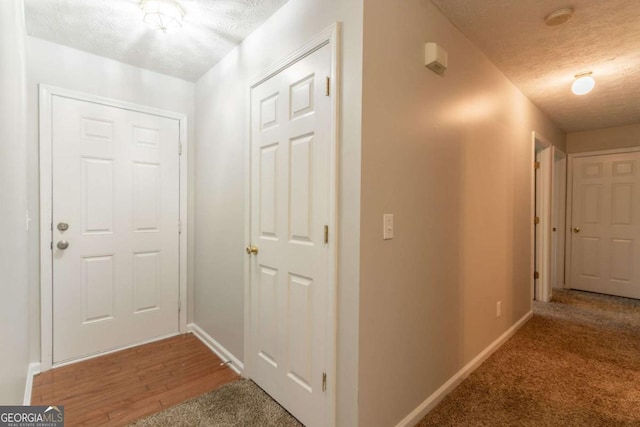 hallway with baseboards, carpet flooring, and a textured ceiling