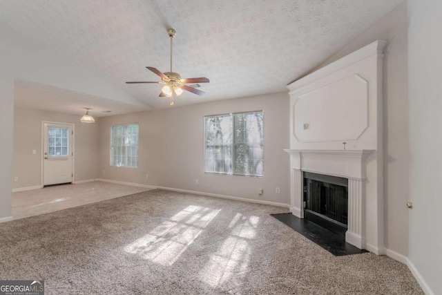 unfurnished living room featuring a ceiling fan, a fireplace with flush hearth, a textured ceiling, baseboards, and light carpet