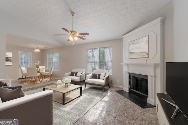 living room with a fireplace with flush hearth, a textured ceiling, baseboards, ceiling fan, and vaulted ceiling
