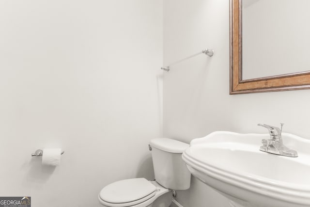bathroom with toilet, baseboards, and a sink