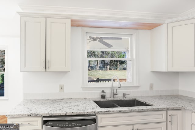 kitchen with ceiling fan, light stone counters, dishwasher, a sink, and white cabinetry