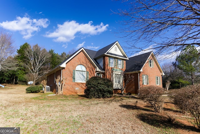 traditional-style home featuring central air condition unit, a front lawn, and brick siding