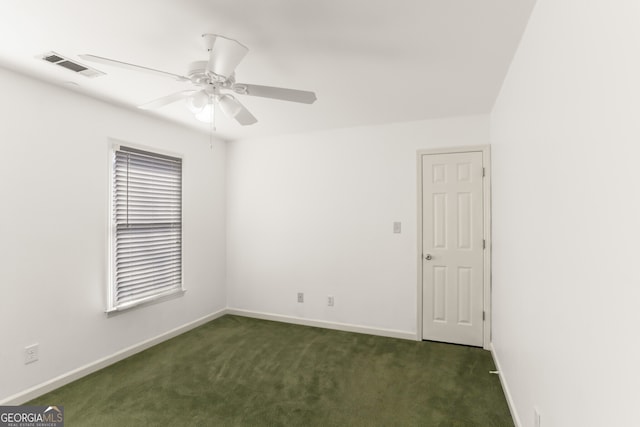 spare room featuring baseboards, dark colored carpet, visible vents, and ceiling fan