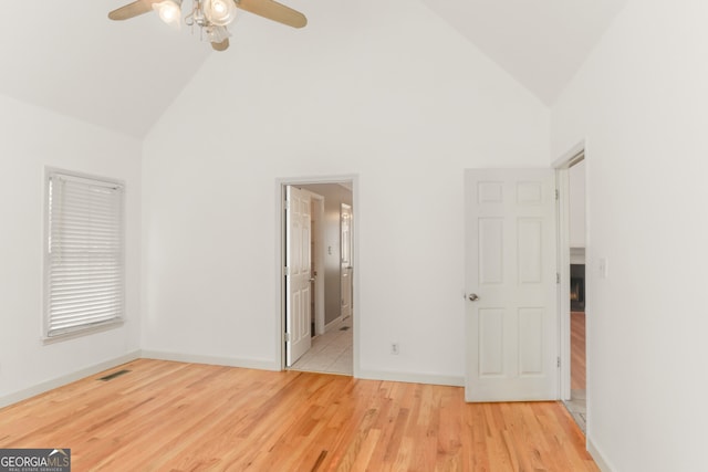 unfurnished bedroom with wood finished floors, visible vents, a ceiling fan, baseboards, and high vaulted ceiling