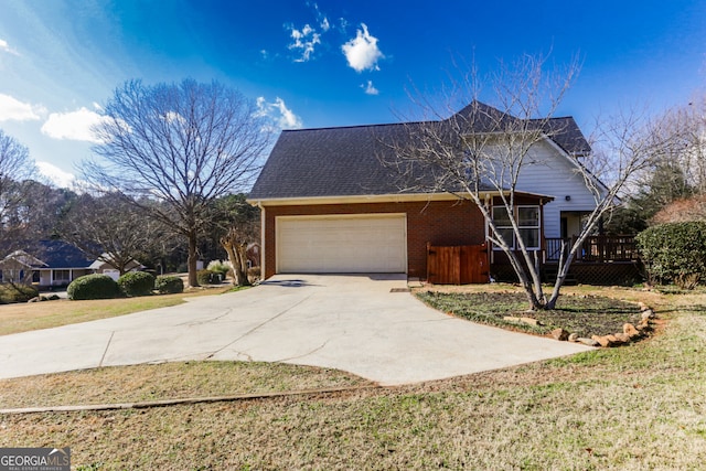 view of side of home with a yard, a wooden deck, driveway, brick siding, and a garage