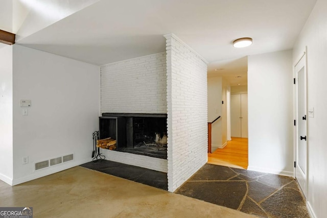unfurnished living room with baseboards, a brick fireplace, and visible vents
